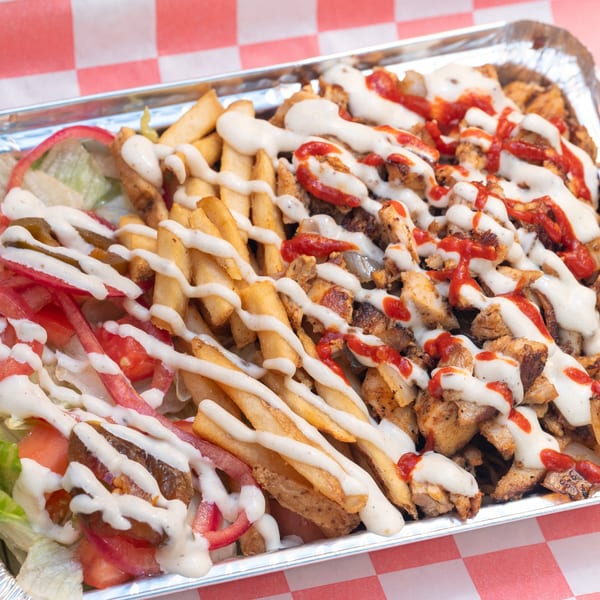 Halalbee's chicken and fries platter with white and red sauces, and a side salad.