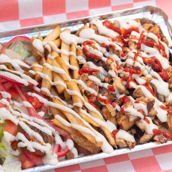 Halalbee's loaded fries with chicken, white sauce, and red sauce in a foil container.